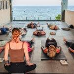 yoga instructor with class at wellness retreat with ocean view wide angle